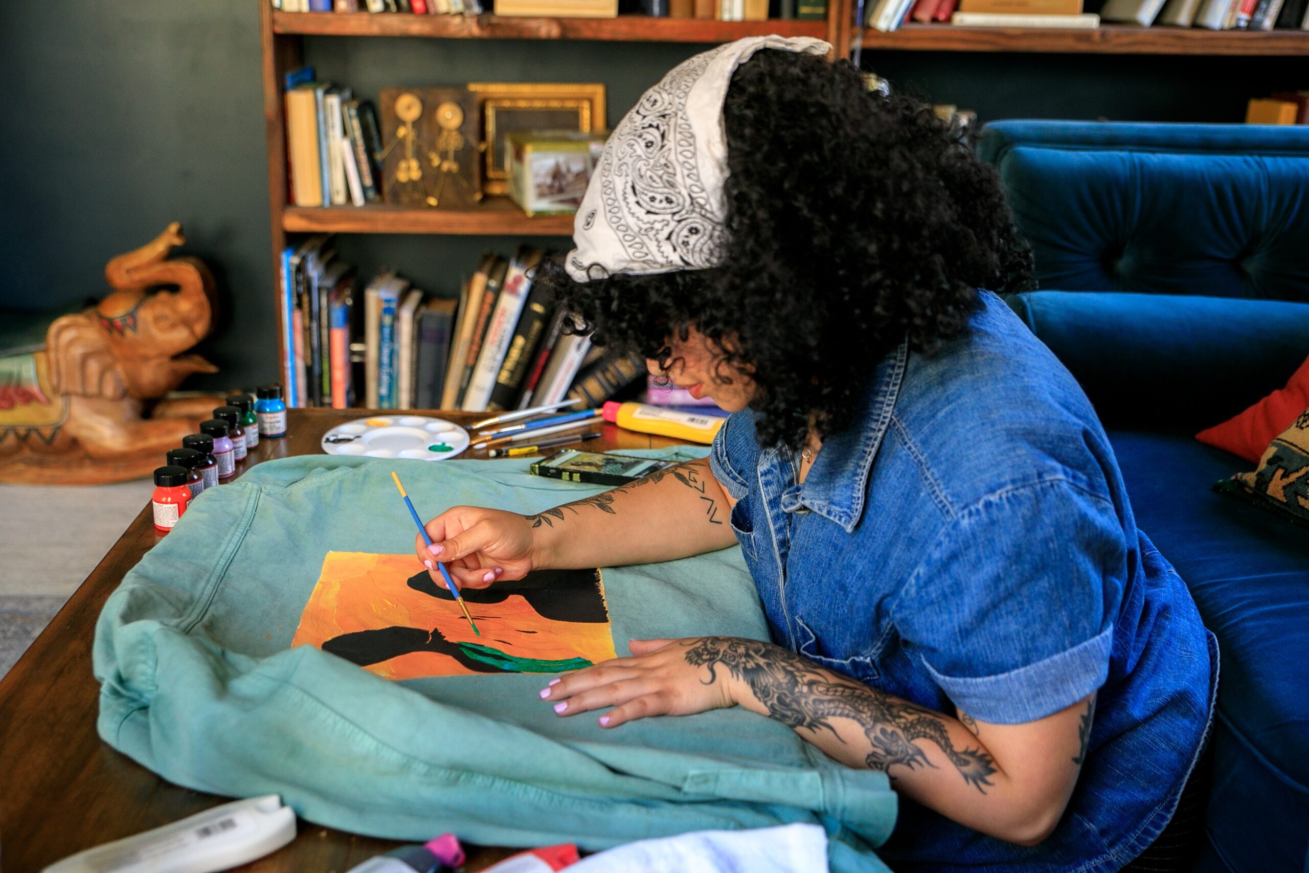 woman with curly hair painting jean jacket